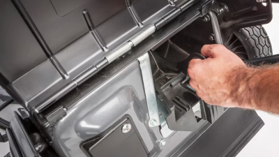 A person’s hand is shown in close-up starting a Honda mower.  