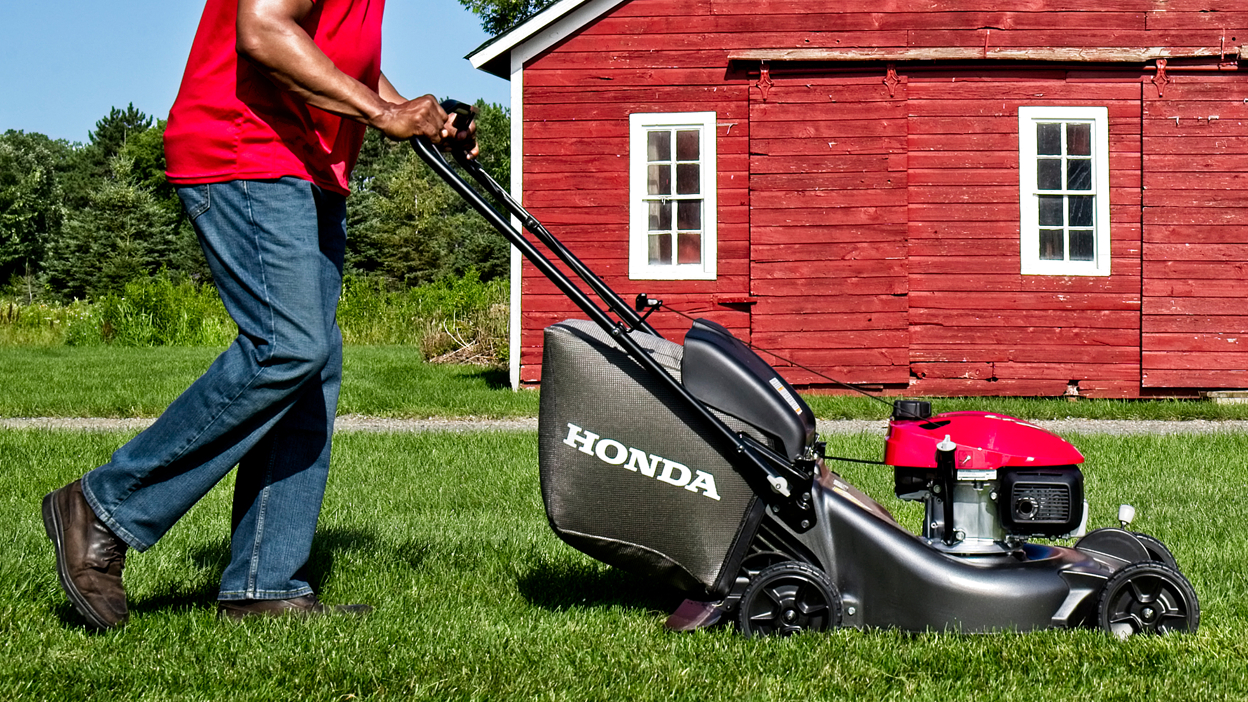 Person mowing lawn going right. Red barn in background.